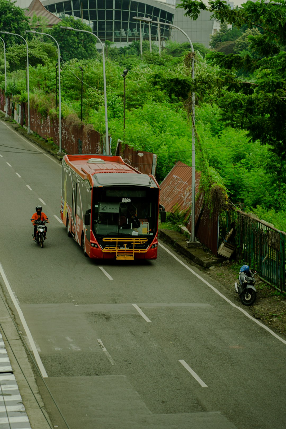 a-red-bus-driving-down-a-street-next-to-a-motorcycle-fq7ynmpb6da